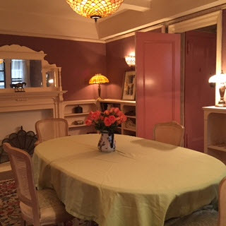 Dining room modeled after Mark Twain's library with rose walls, low bookcases, Tiffany lamp and overhead light