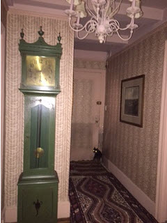 Wallpapered hallway with grandfather clock, crystal chandelier and turkish carpet