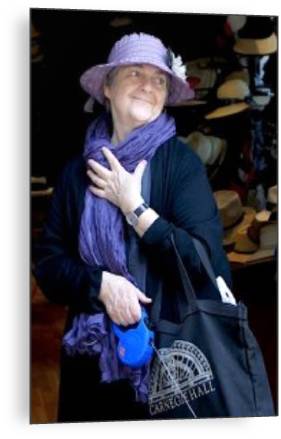 Barbara Sher in a purple hat and scarf in a hat shop